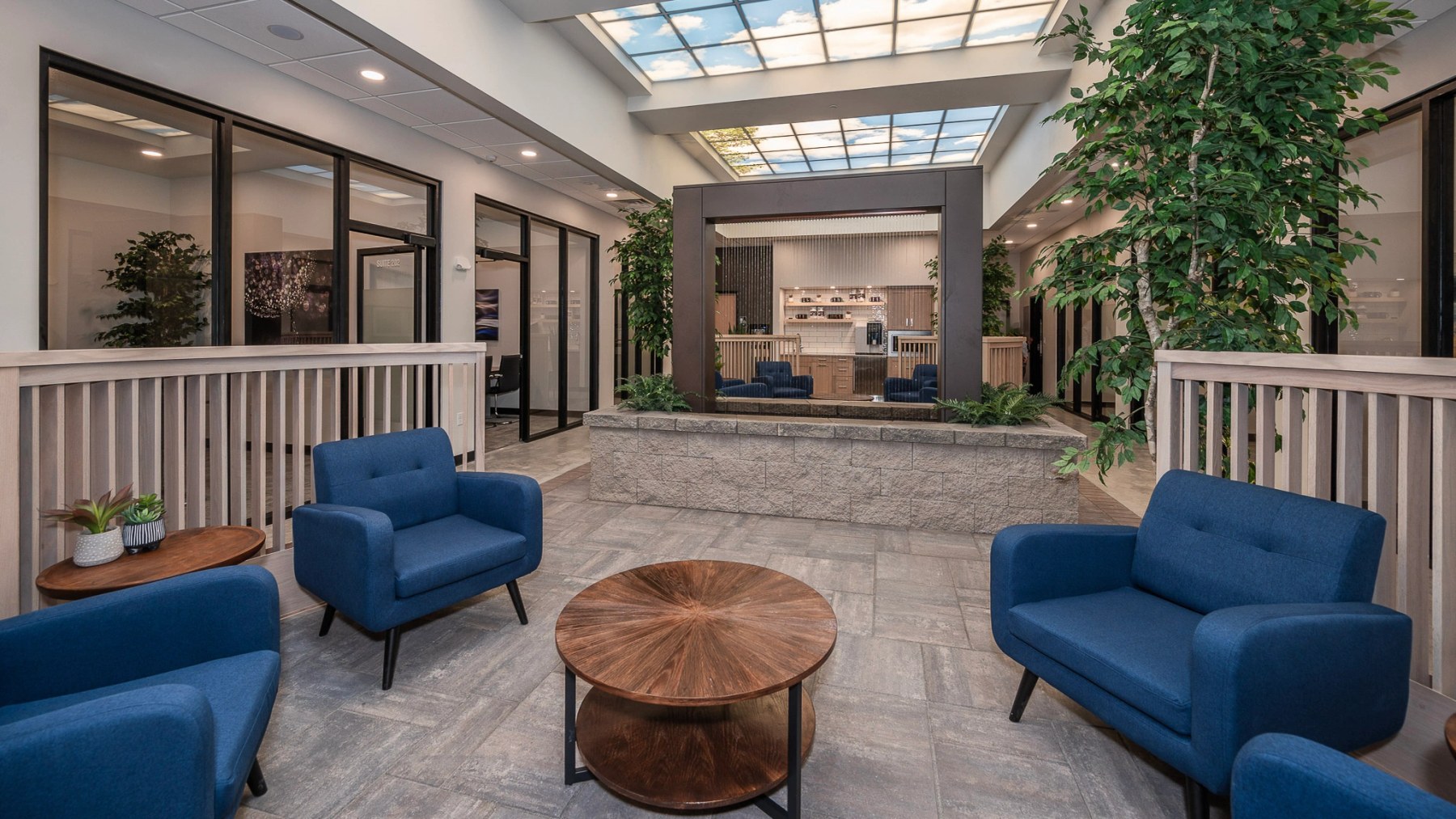 Comfortable blue lounge chairs, a central waterfall, and glass-front private offices at Atrium