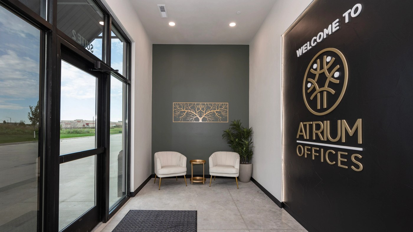 Atrium's glass entryway and waiting area with its illuminated office sign