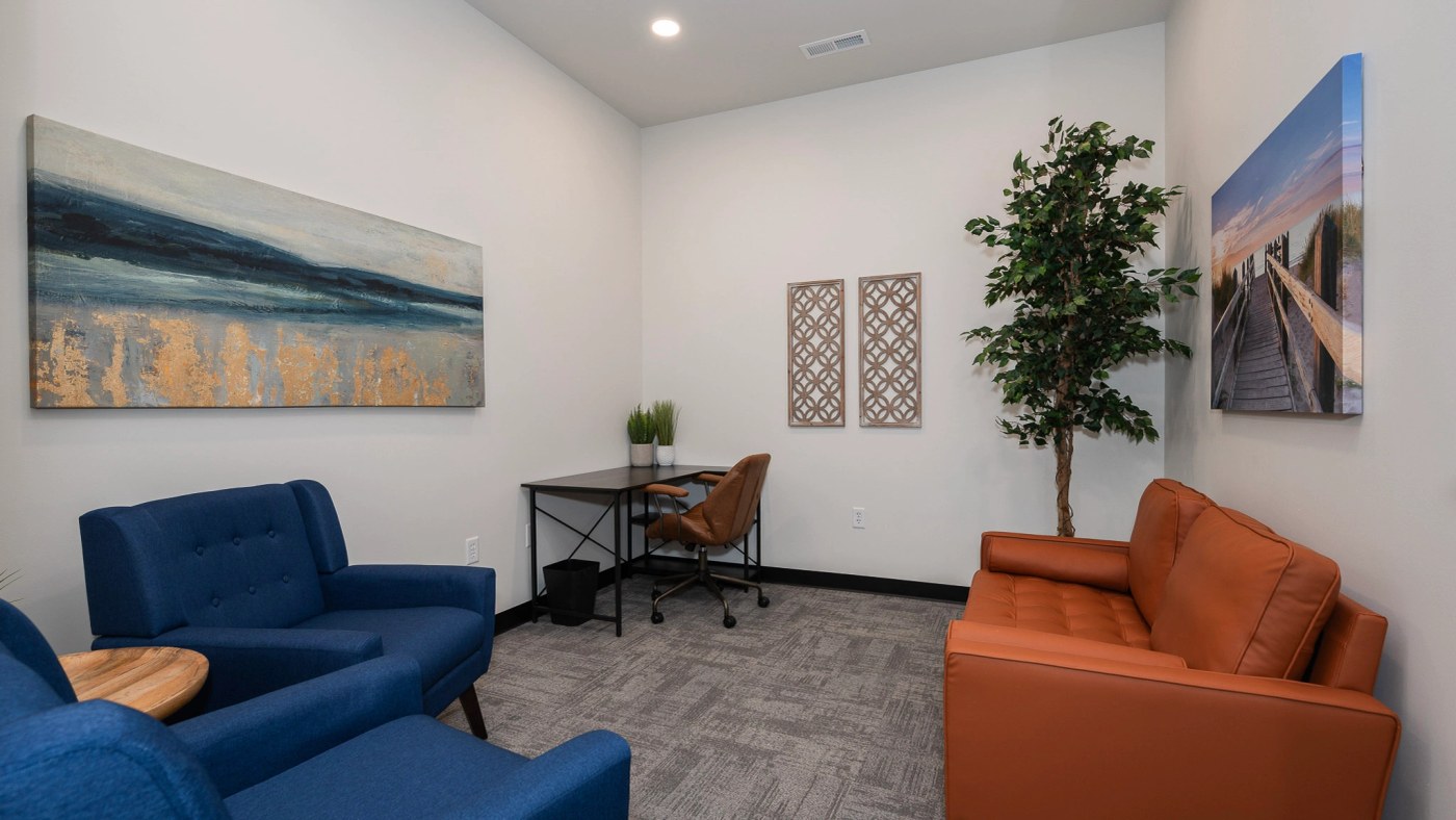 The lounge suite with a desk, blue armchairs, and a comfortable orange sofa