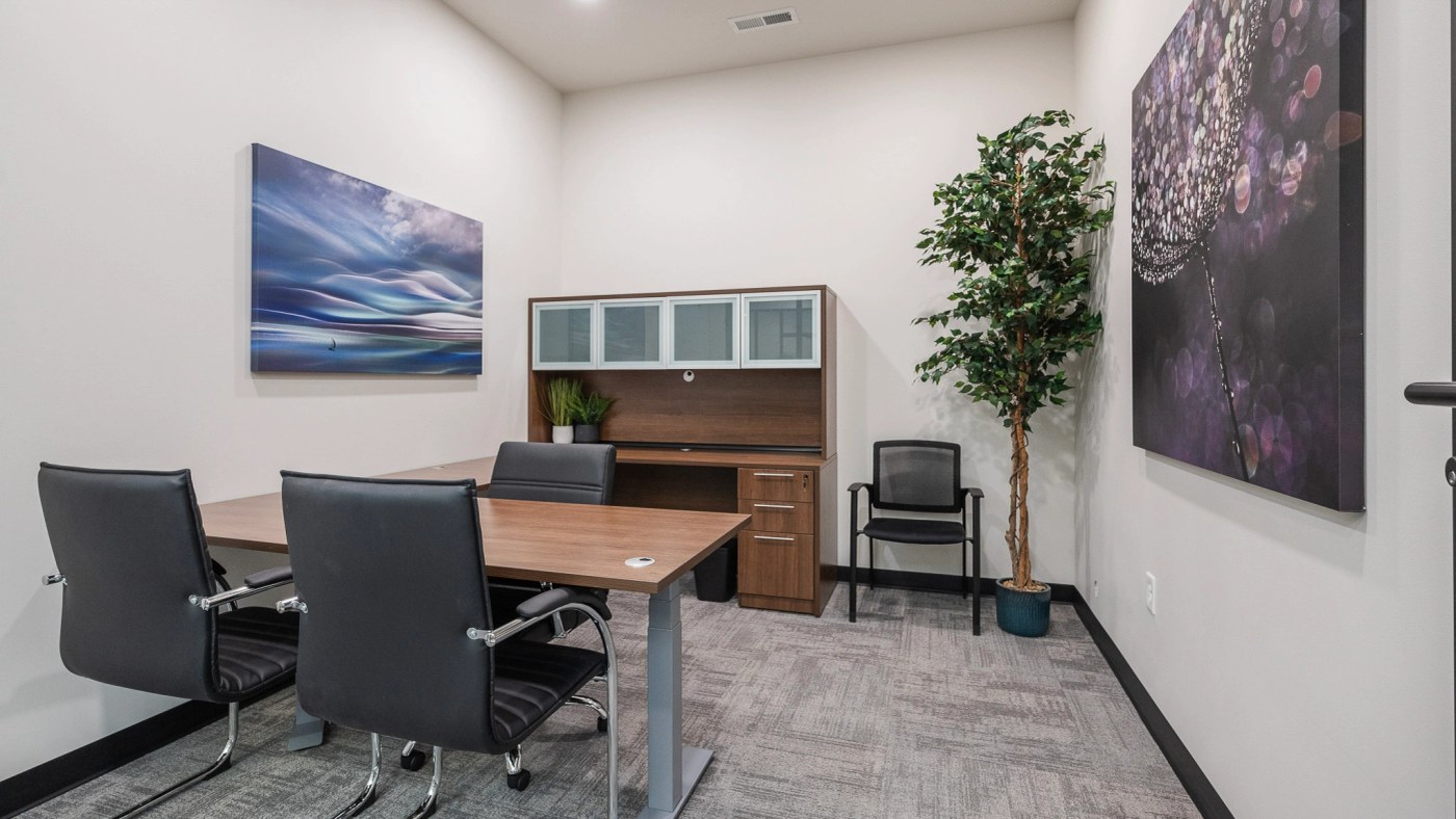 A fully furnished private office with a desk and chairs at Atrium